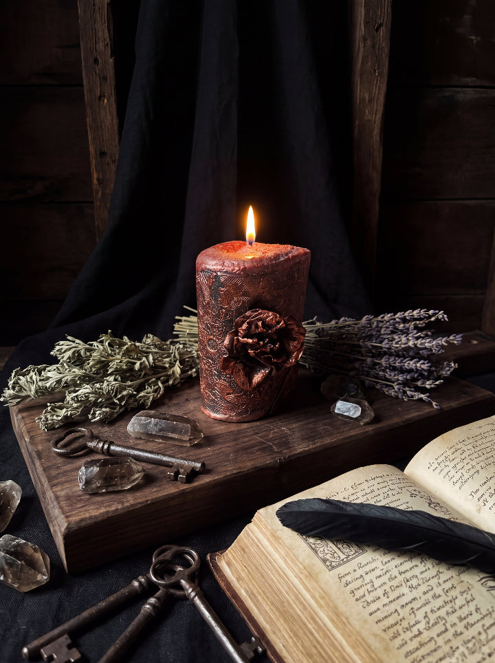 Corrosion candle burning beside dried herbs, crystals and antique keys
