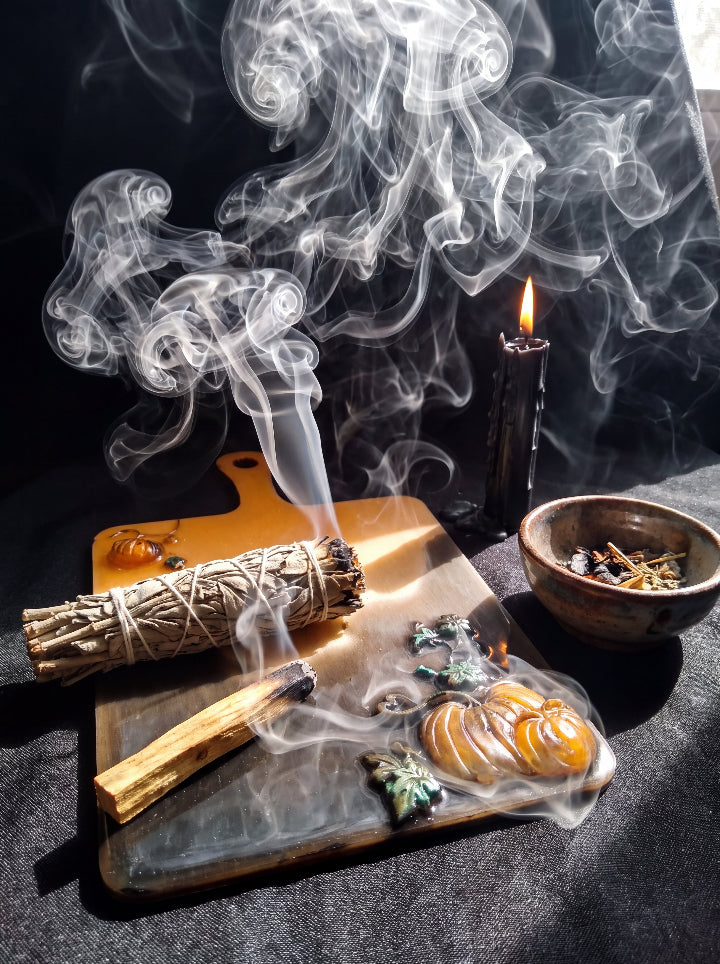Salem Board with pumpkin details beside a smoking herb bundle and black candle