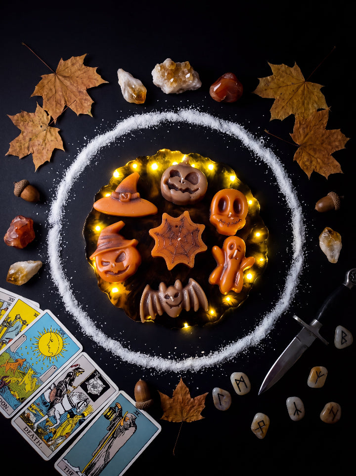 Spellbound Halloween beeswax candles on a glowing resin stand, surrounded by autumn leaves, crystals and tarot cards.