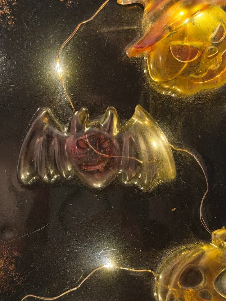 Close-up of a translucent resin bat beside a glowing pumpkin on The Midnight Portal