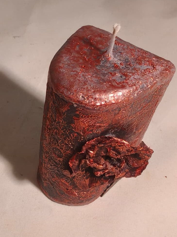 Angled close-up of Corrosion beeswax candle showing its bronze textured finish and single wick